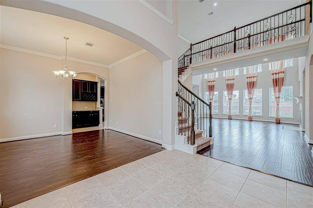 This view highlights the welcoming formal dining room, the bright and open living room with high ceilings, and the staircase near the entrance.