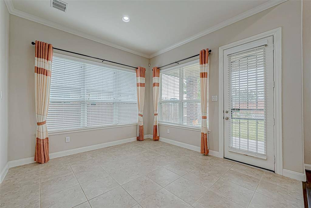 The breakfast room is filled with natural light, creating a warm and inviting space. A door leads directly to the backyard, offering easy access to outdoor dining or relaxation.