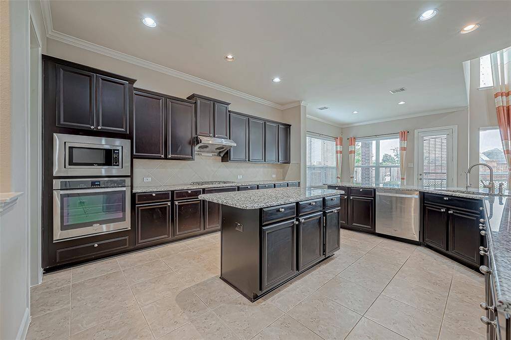 The kitchen features stunning granite countertops, including a central island that adds both functionality and style. Dark wood cabinets provide a rich contrast, creating an elegant and inviting cooking space.
