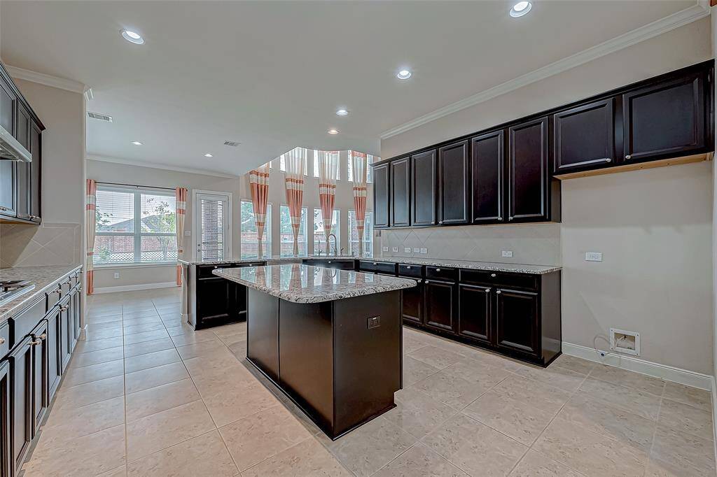 The kitchen features stunning granite countertops, including a central island that adds both functionality and style. Dark wood cabinets provide a rich contrast, creating an elegant and inviting cooking space.