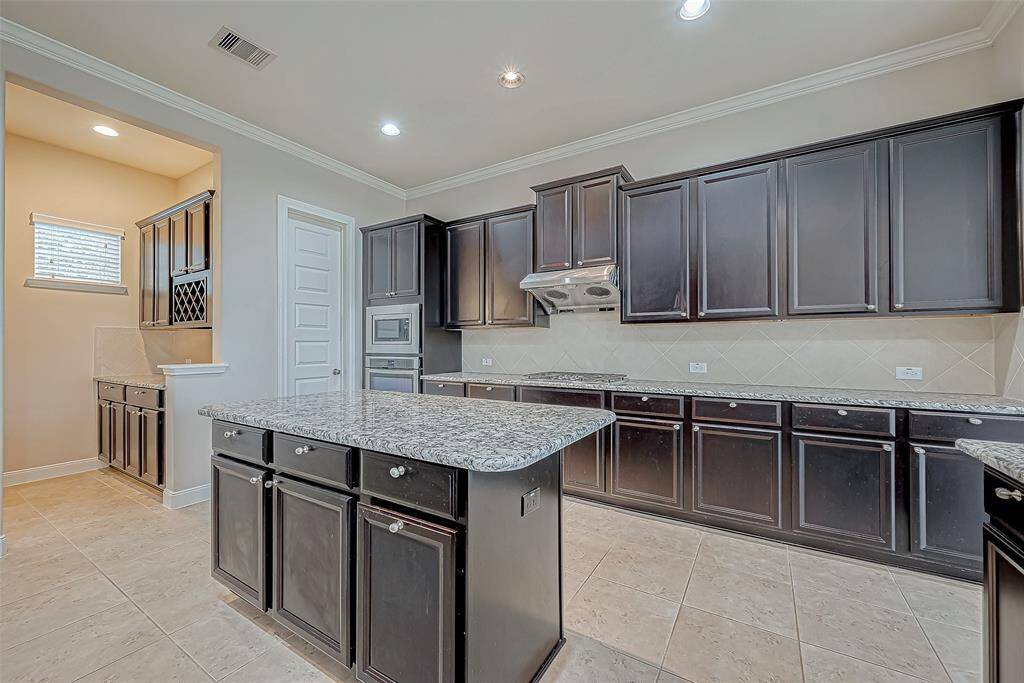 The kitchen is enhanced with stunning granite countertops, a central island, and dark wood cabinets. A wine cellar room adds a touch of sophistication, perfect for wine enthusiasts and ideal for entertaining guests.