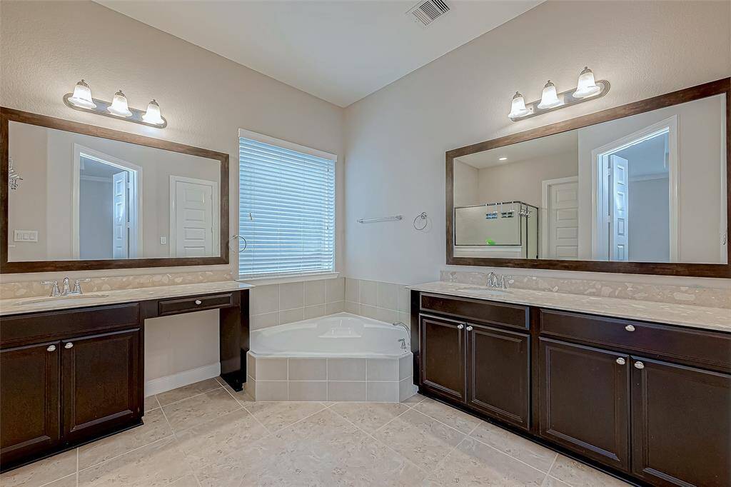 The master bathroom features a double sink vanity, offering plenty of space for shared use. It also includes a separate bathtub and shower.
