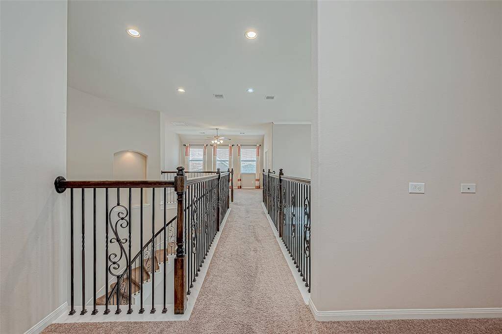 Upstairs, a long walkway leads to a game room or common area, along with several bedrooms. This layout creates a functional and spacious area, perfect for family activities and relaxation.