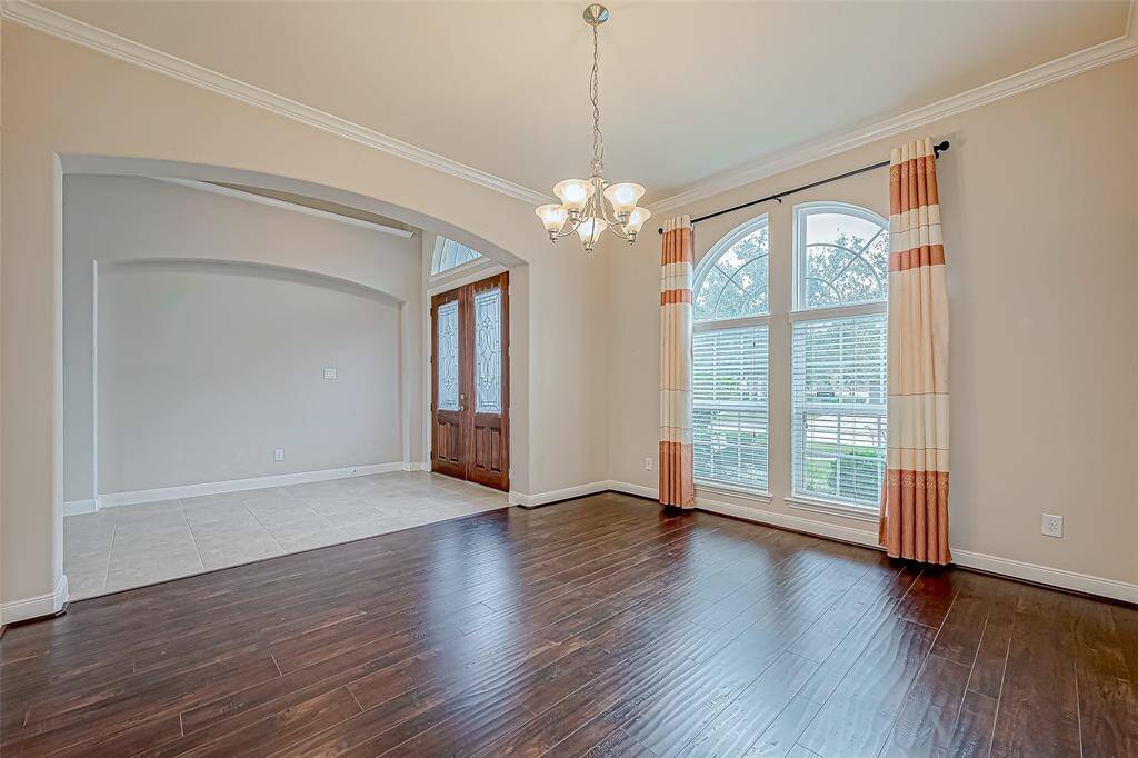 This formal dining area features elegant lighting and beautiful wood flooring, creating a warm and inviting space for gatherings.