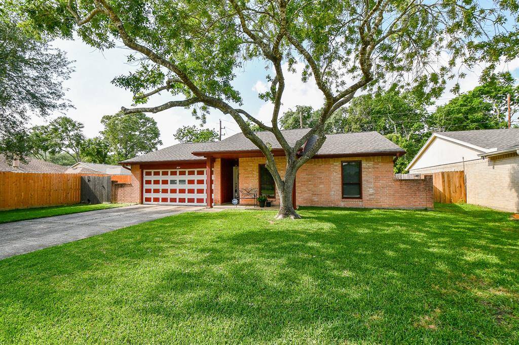 Charming single-story brick home and a spacious front yard. Features a large mature tree, a well-maintained lawn, and a welcoming front porch.