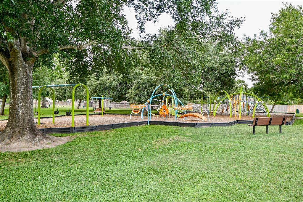 Playground set is a favorite in this lush, green park. It features swings, climbing structures, and slides under the shade of large trees, ideal for family recreation.