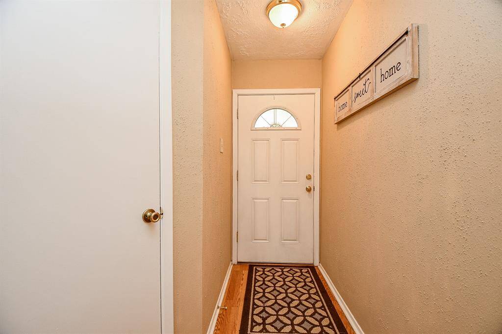 Entryway with light fixture, and a coat closet Features a white front door with window and neutral wall tones.