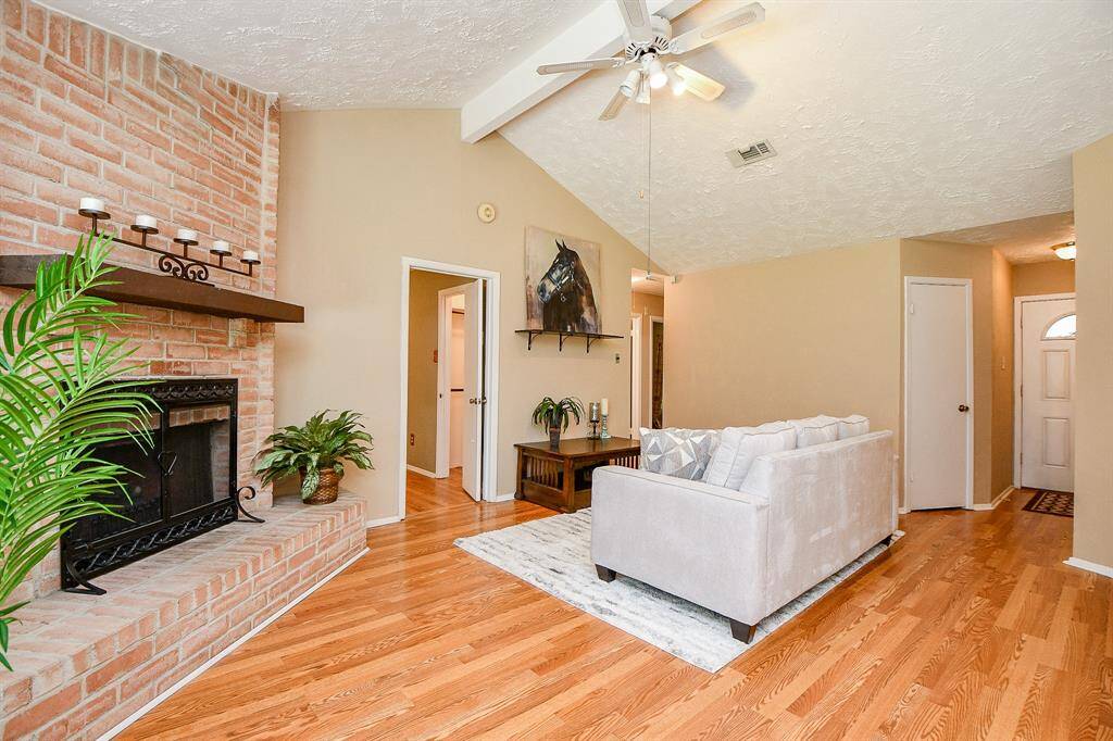 Wood burning brick fireplace, and warm hardwood floors, open layout creating a welcoming atmosphere for relaxation and entertainment.