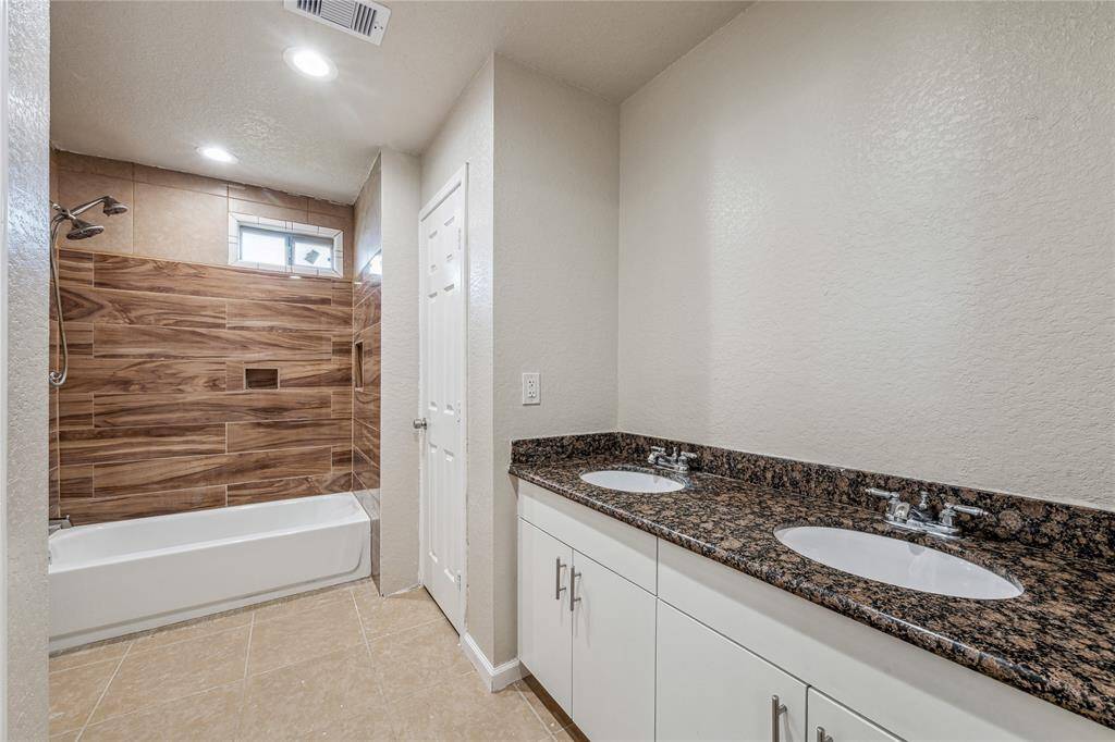 Luxurious secondary bathroom featuring dual sinks and shower/tub combo.