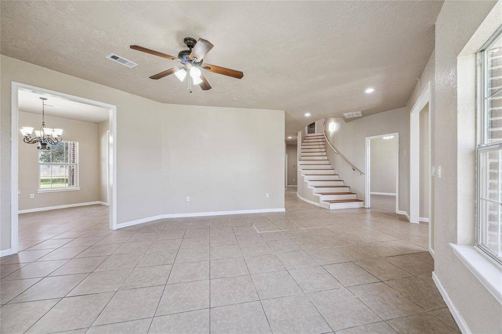 Bright and inviting living room with neutral tones and elegant tile flooring, ready for your personal touch.