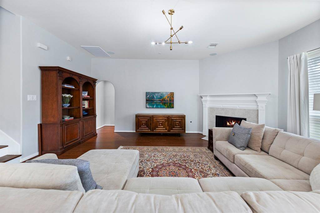 This spacious living room offers a warm and inviting atmosphere, anchored by a classic fireplace and framed by clean architectural lines.
