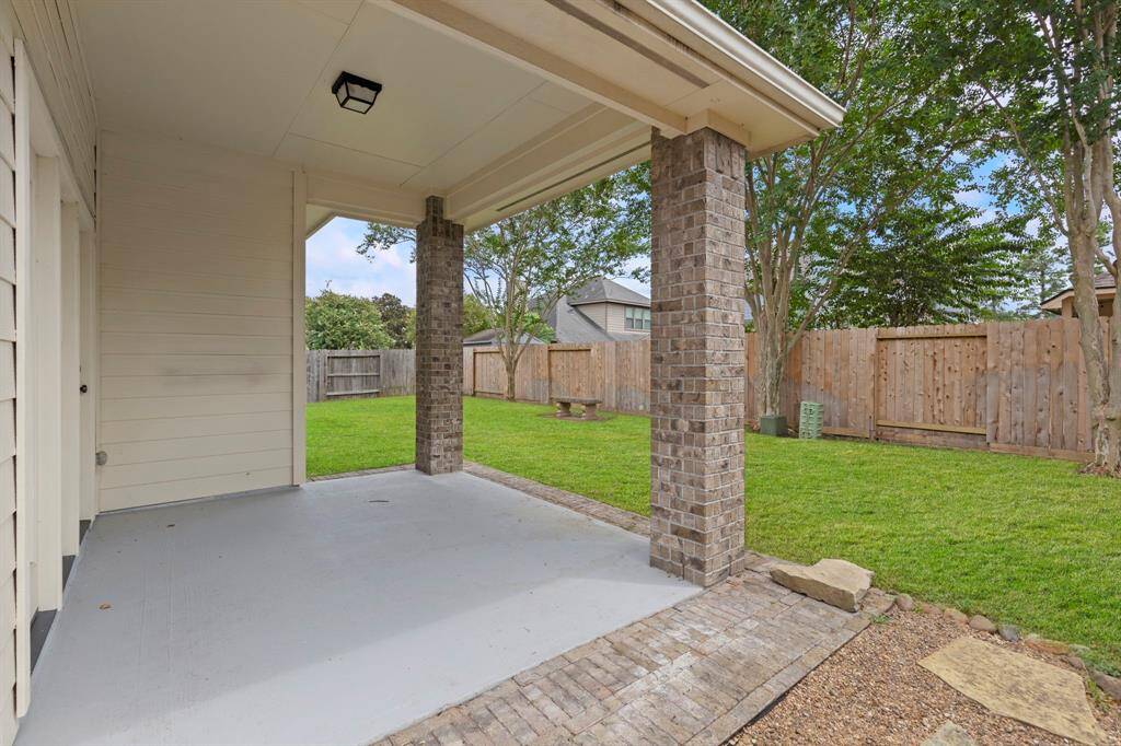 Enjoy outdoor living under the covered patio, complete with brick columns and a spacious, fully fenced backyard with mature trees—perfect for relaxing or entertaining.