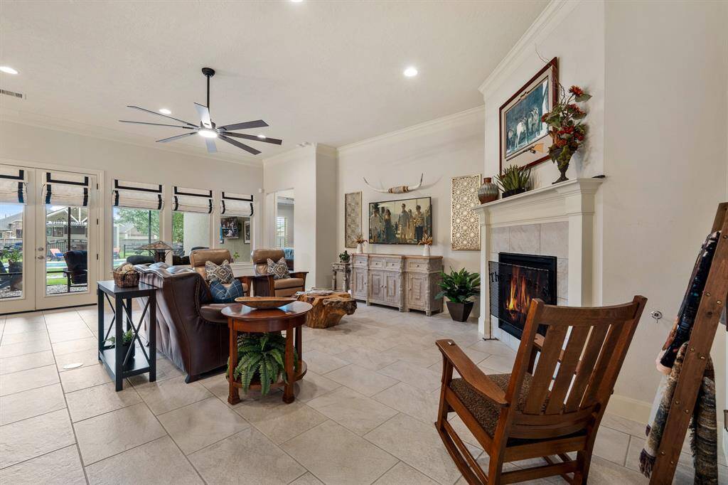 This view of the Family Room showcases the crown molding, custom window coverings, extra wide baseboards, and upgraded, 8-blade ceiling fan. The opening straight ahead leads to the Primary Suite.