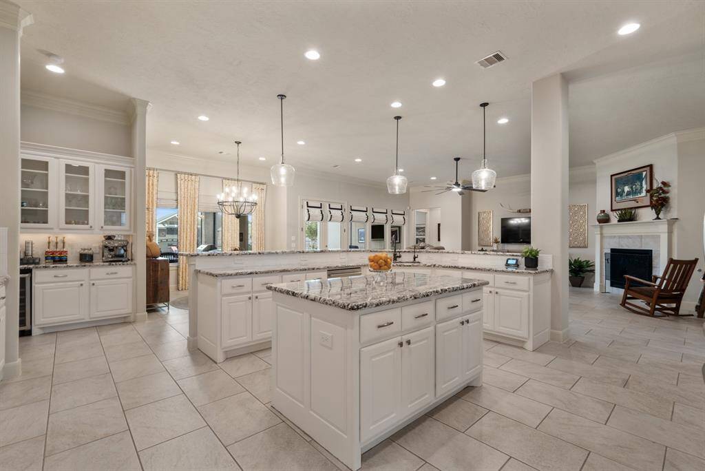 This view showcases the custom designed Island and the extra prep space it offers. Look at the abundance of cabinets and drawers for additional storage! The dual basin, undermount sink overlooks the Family Room and includes a pull-down nozzle faucet.