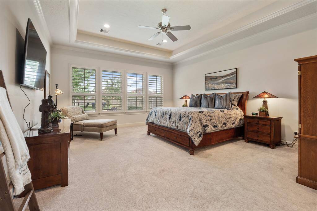 Relax and unwind in the comfort of this spacious Primary Suite. Adorned with wall-to-wall plush carpeting, a quartet of cased windows, plantation shutters, trey ceiling, and crown molding, this space is sure to suit all your needs…and more.