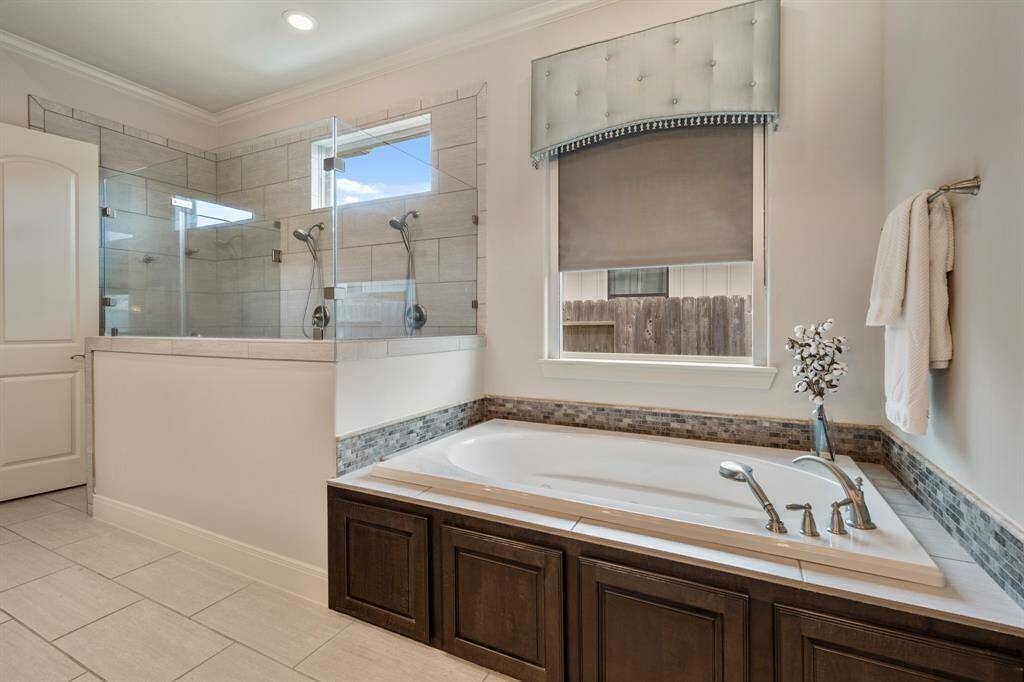 Wash away the stress of the day in this oversized walk-in shower finished with dual shower heads. The clear glass pony wall allows natural light to spill into the Bathroom from the picture window above. This built-in, Whirlpool tub includes a detachable spray nozzle, making it easier to rinse off before exiting.