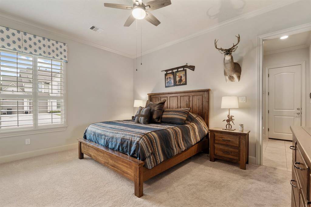 This spacious Secondary Bedroom boasts an ensuite Bathroom, wall-to-wall plush carpeting, crown molding, a walk-in closet, and window adorned with plantation shutters. There is plenty of room for additional storage pieces, a TV, and/or a small desk.
