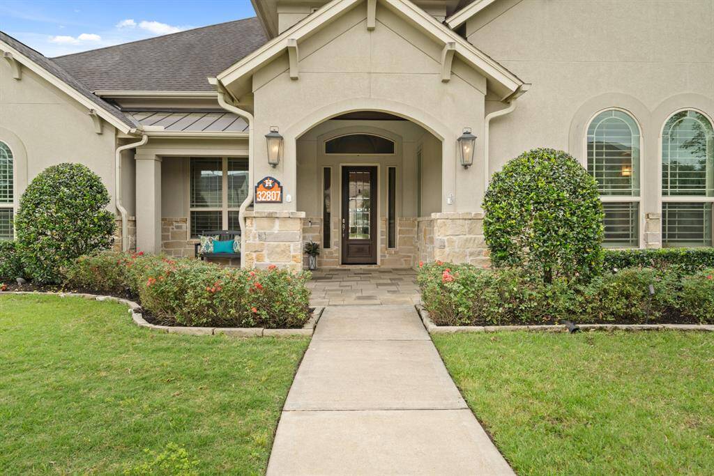 Guests will trapse down the well-lit Front Walkway, through the stacked stone-lined garden beds, and approach this elegant glass-plated front door with sidelights and transom above. The spacious Front Porch is floored in slate tiles and topped with a beadboard ceiling.