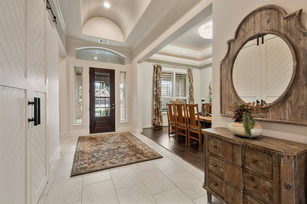 Notice the abundance of natural light that spills into the Foyer through the glass-plated front door, sidelights, and transom above. This elongated Foyer can easily accommodate a bench or storage piece. The barn doors to the left lead into the home Office, while the Dining Room can be seen in the opening to the right.