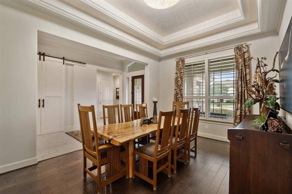 Friends and family will enjoy gathering in this spacious Dining Room. The space boasts engineered wood flooring, a double trey ceiling, high-end chandelier, and a front facing window adorned with plantation shutters.