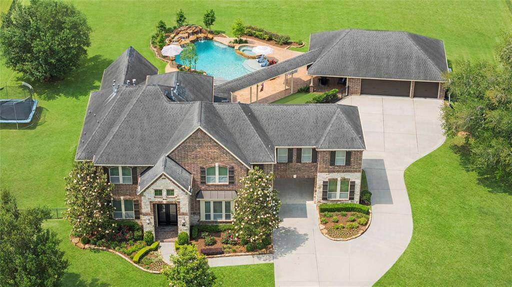 This breathtaking aerial view from the front captures the grandeur of this luxury home, elegantly situated on an expansive lot in the prestigious, guard-gated community of Weston Lakes.