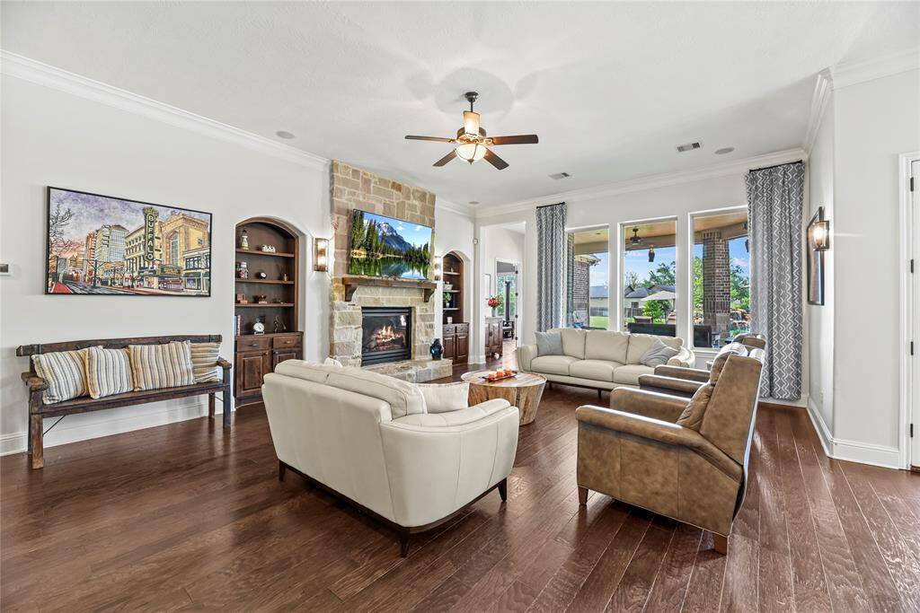 The impressive stone fireplace serves as a stunning focal point, beautifully complemented by custom built-in shelving that combines refined craftsmanship with functional elegance, elevating the room’s overall sophistication.