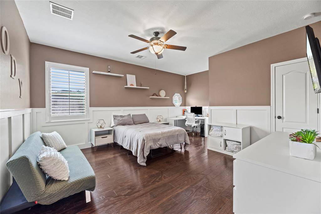 The generously sized fourth bedroom is adorned with rich engineered wood flooring and bathed in natural light from a large, bright window, creating a welcoming and airy retreat.