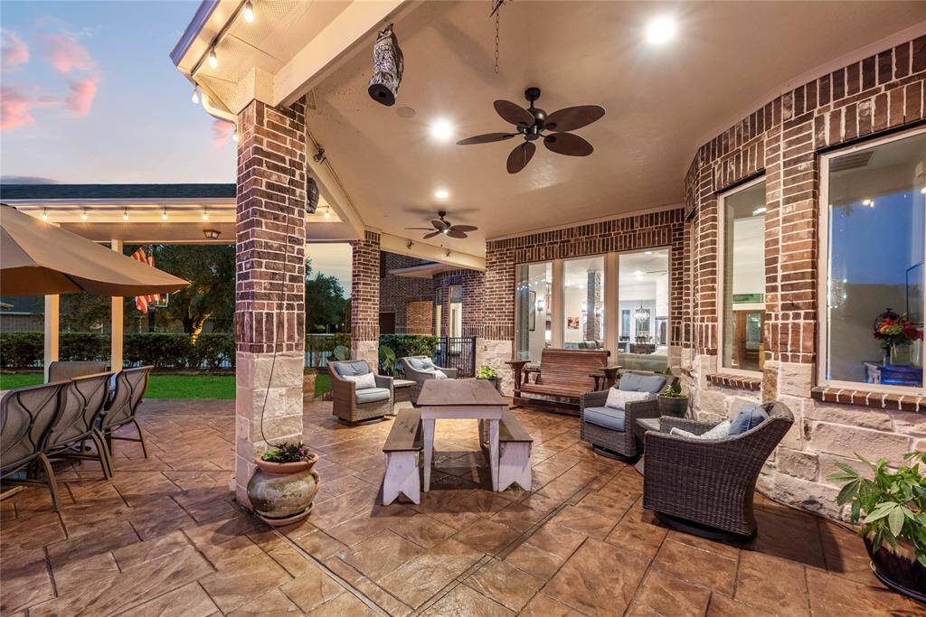 The covered patio and deck feature an elegant seating area, offering a serene outdoor retreat, ideal for relaxing or entertaining in style, while enjoying the beauty of nature in complete comfort and sophistication.