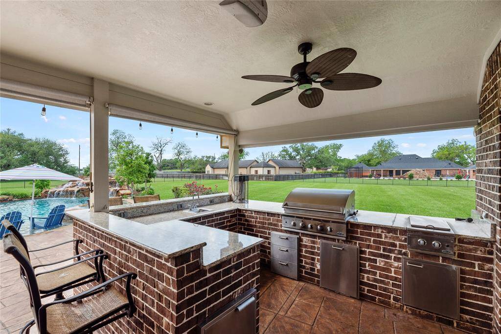 The outdoor kitchen, ideally located near the pool, is a culinary masterpiece designed for effortless entertaining, featuring high-end appliances, ample prep space, and a sleek, stylish layout that enhances both form and function for a truly luxurious al fresco experience.