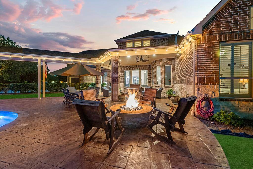 The custom-designed fire pit radiates a captivating glow, perfectly complemented by the soft backlighting of the patio, creating an ambiance of effortless luxury and serene sophistication.