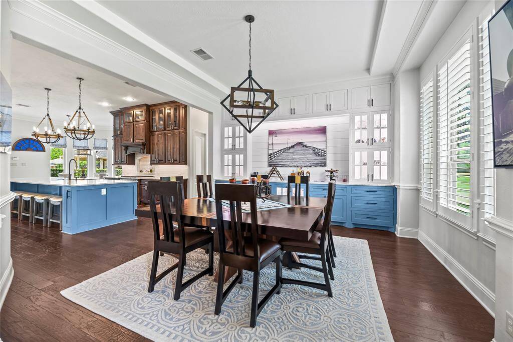 To the right of the entry, the formal dining room boasts custom built-in cabinets with glass doors to elegantly display your finest stemware, complemented by a stunning chandelier. This exquisite space, perfect for entertaining, also serves as an ideal butler's pantry, offering both functionality and refinement in every detail.