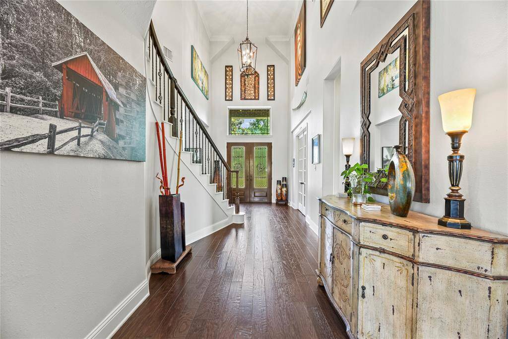 The foyer exudes timeless elegance with its gleaming engineered wood floors and a dazzling chandelier that adds a touch of refined sophistication to the welcoming entry.