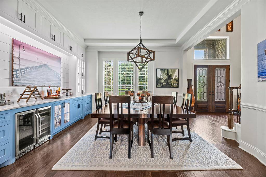 This exceptional space is defined by soaring vaulted ceilings, crown molding, and a sophisticated beverage fridge seamlessly integrated into custom cabinetry. Large windows, framed by custom shutters, invite an abundance of natural light, infusing the room with a bright and welcoming ambiance.