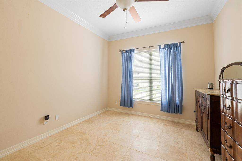 Secondary bedroom that features tile floors, ceiling fan, and ensuite bathroom.