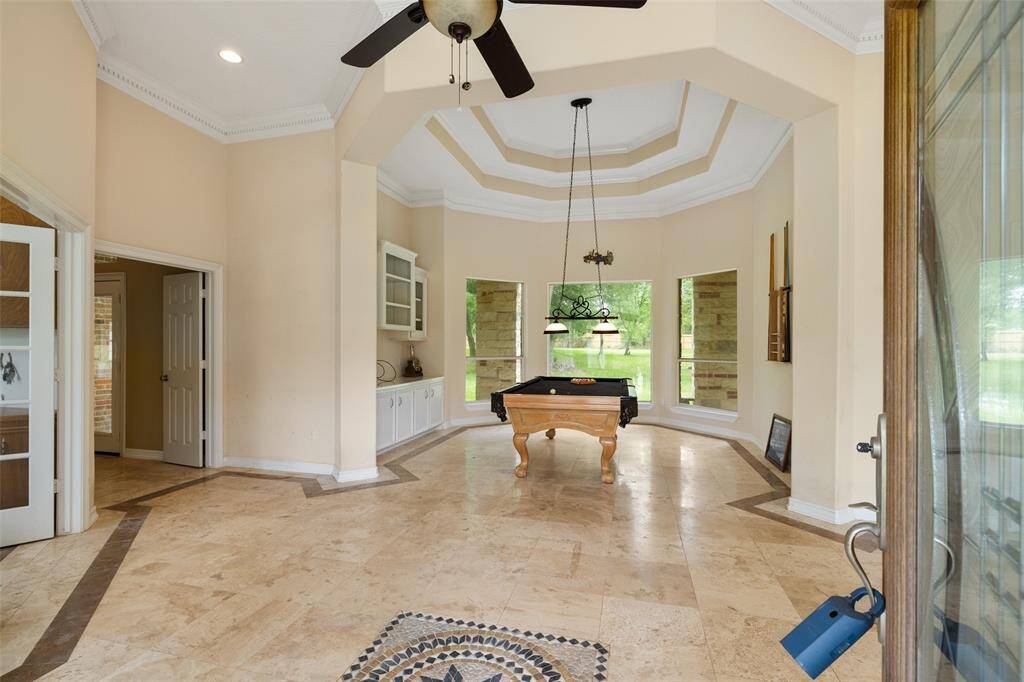 This spacious foyer features tile flooring, crown molding, and a high ceiling with a ceiling fan.