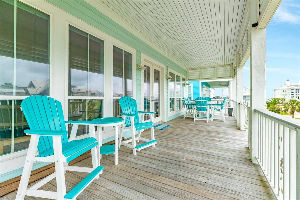 This inviting coastal home features a spacious wooden deck with vibrant turquoise furniture, perfect for relaxing or entertaining while enjoying scenic views.