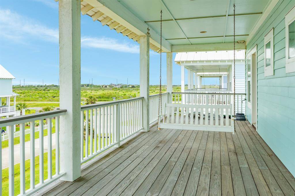 Charming covered porch with a wooden swing, overlooking lush greenspace. Ideal for relaxation and enjoying serene views.
