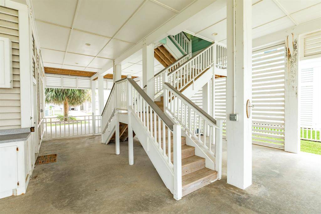 The space features white railings and columns, providing a clean and airy feel. It's ideal as an entertainment area, with views of greenery.