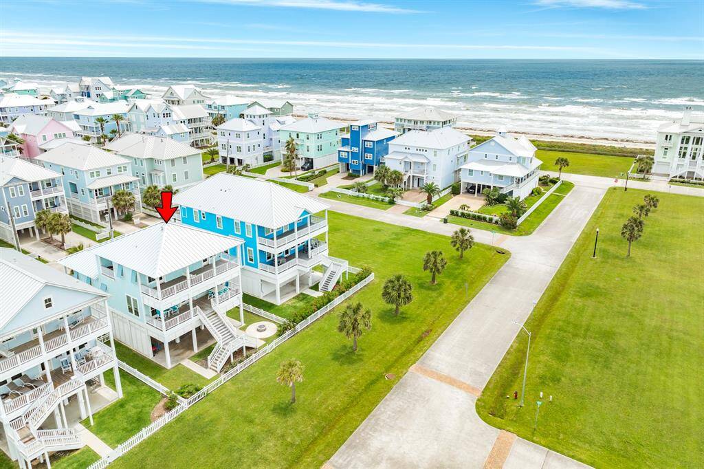 3810 Abalone is a charming two-story home with a spacious decks, offering stunning ocean views. It's located in a picturesque neighborhood with easy beach access, lush green lawns, and palm trees, perfect for seaside living.