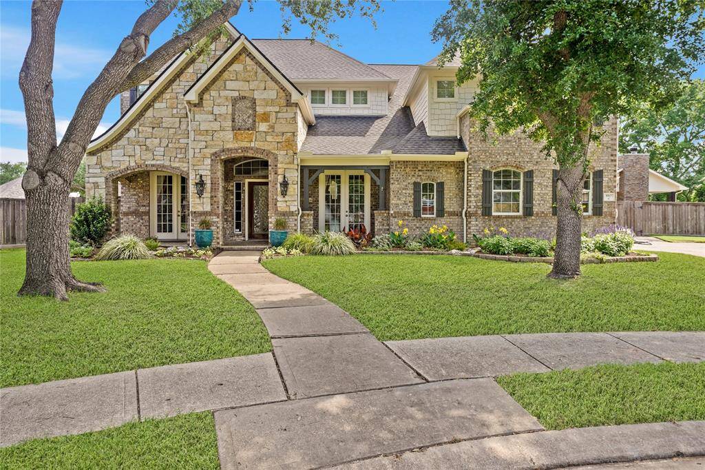 Charming two-story home with a stone and brick exterior, featuring a well-maintained front yard and inviting walkway. The house is accented by mature trees, large lot size and landscaped flower beds, creating great curb appeal.