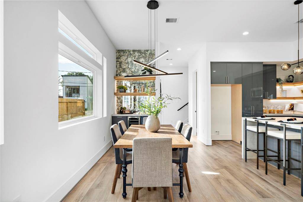 The dry bar is a showstopper, featuring elegant floating shelves and a stunning stained antique glass backsplash that extends all the way to the ceiling, adding a touch of timeless charm.