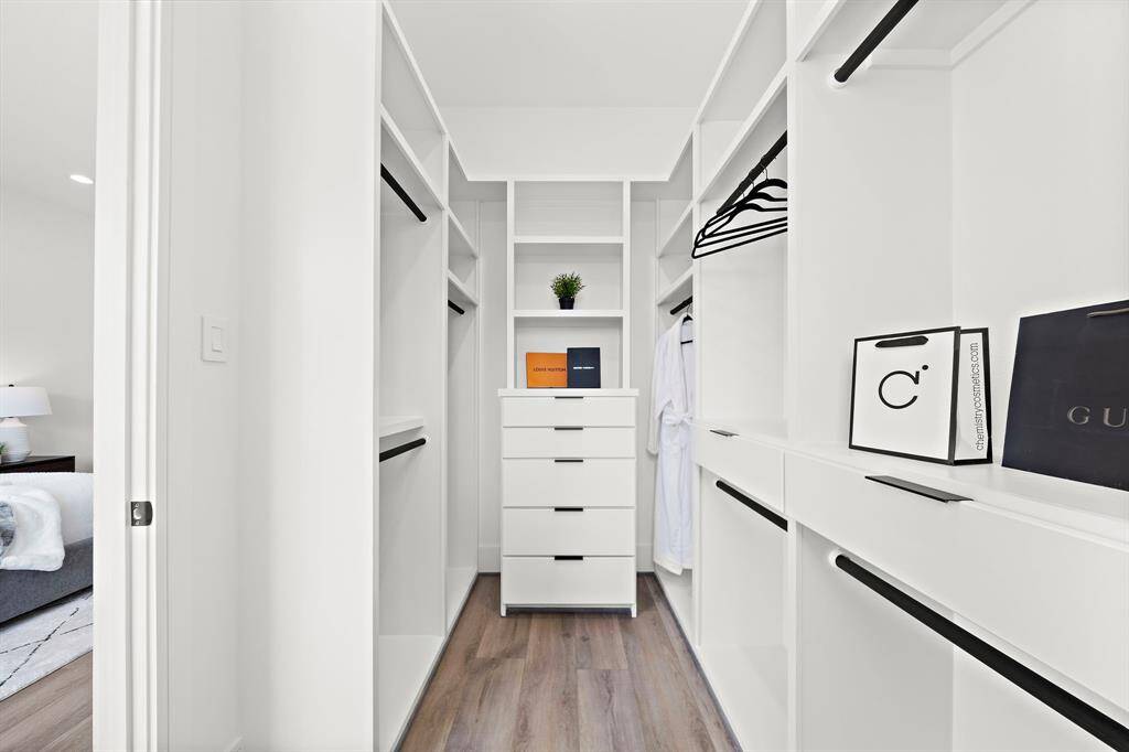 Here’s a look into one of the primary closets, featuring a built-in dresser and ample space for hanging garments and dresses, combining style with practicality.
