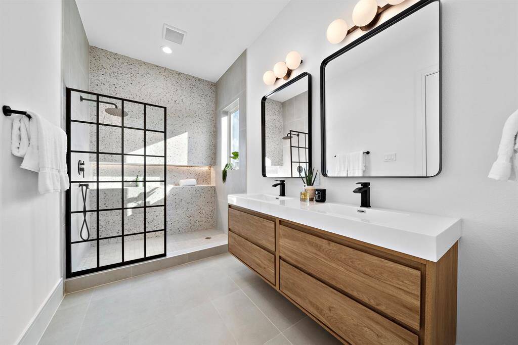 The primary ensuite bath is straight out of an HGTV magazine, showcasing floating his-and-hers sinks, a spacious walk-in shower, and a generously sized shower niche elegantly underlit by LED lighting.