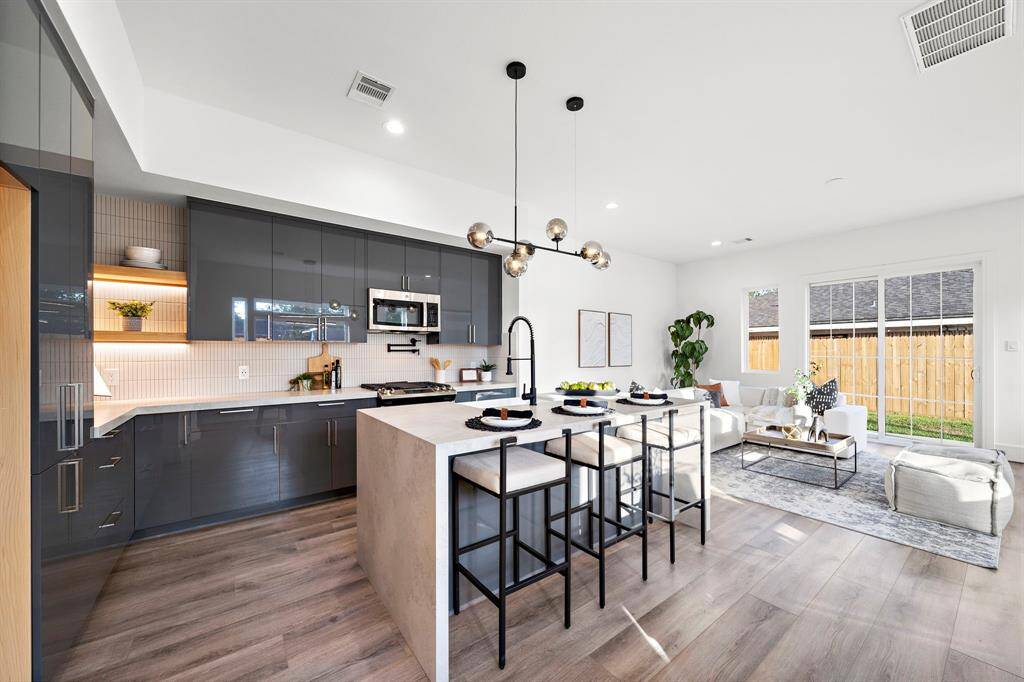 This chef's dream kitchen is a true retreat, featuring a stunning double waterfall island with thick quartz-wrapped countertops, a sleek single farmhouse porcelain sink, and a convenient pot filler for effortless cooking.