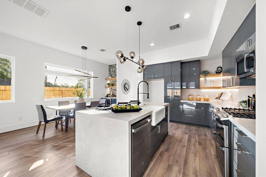 The kitchen flows effortlessly into the dining area and dry bar, all beautifully illuminated by natural light streaming through expansive custom windows.