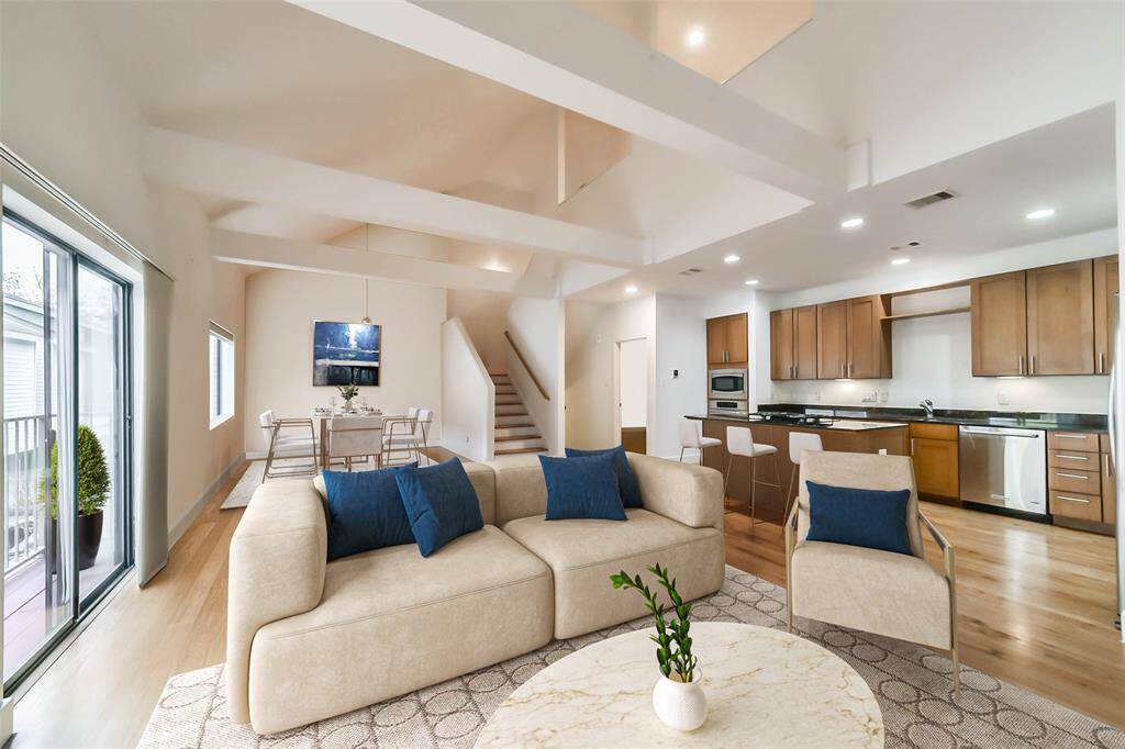 Living room featuring double sliding glass doors to the private balcony and double-height vaulted ceilings. Virtually staged.