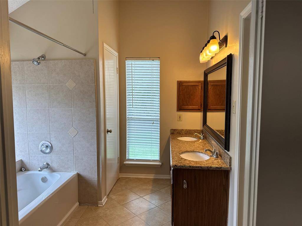 Primary bathroom with double sink and tub/shower combo.