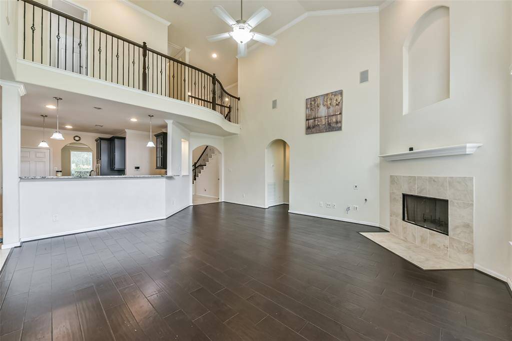 Living room features beautiful flooring, aceiling fan, high ceilings, and large windows.