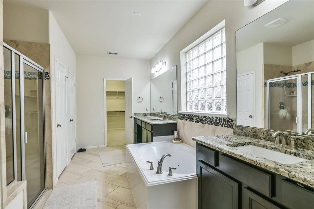 The primary bathroom features tile floors, dual sinks, walk-in shower, and separate tub.