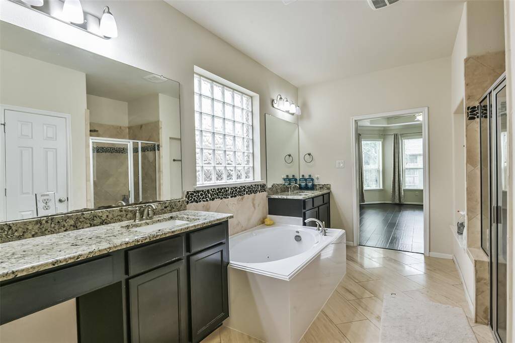 The primary bathroom features tile floors, dual sinks, walk-in shower, and separate tub.
